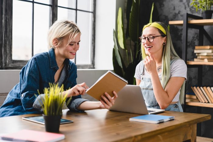 two women social media managers sitting at a table looking at a laptop, planning social media strategy preview image